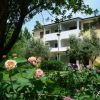 Edificio giallo, giardino con fiori, alberi ombrosi.