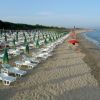 Spiaggia con lettini e ombrelloni colorati.