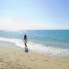 Persona cammina sulla riva del mare sotto il sole.