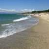 Spiaggia con sabbia e onde, cielo sereno.