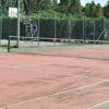 Campo da tennis con asfalto rosso, recintato.
