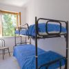 Letto a castello in una stanza bianca, finestra aperta, sedia nera.