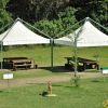 Due tende bianche con tavoli da picnic su prato.