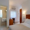 Camera d'albergo con letto singolo e bagno adiacente.