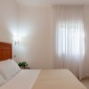 Letto matrimoniale con una finestra coperta da tende bianche.