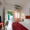 Camera da letto con copriletto rosso e porta aperta verso un patio.