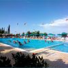 Piscina all'aperto con scivoli e persone che nuotano.