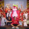 Persone con costume rosa e bambini sorridenti sul palco.