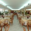Sala ristorante con tavoli apparecchiati e sedie in legno.