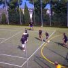 Partita di calcetto su campo esterno recintato.