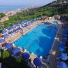 Una piscina circondata da ombrelloni blu su una collina, vista mare.