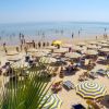 Spiaggia panoramica con ombrelloni a righe fronte mare.