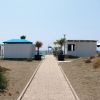 Sentiero tra dune di sabbia e capanni, vista mare.