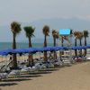 Spiaggia con lettini e ombrelloni blu.