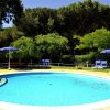 Piscina tonda con lettini e ombrelloni blu.
