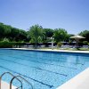 Piscina azzurra con lettini e ombrelloni intorno.