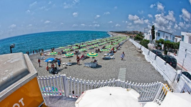 Spiaggia con ombrelloni verdi e gialli sul mare.