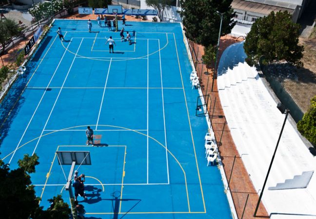 Partita di basket su un campo blu con spettatori seduti.