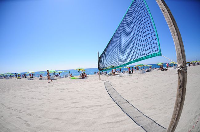 Rete da beach volley su spiaggia con ombrelloni.