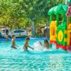Bambini giocano in piscina con giochi d'acqua colorati.