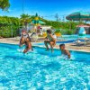 Bambini saltano in una piscina con sdraio attorno.
