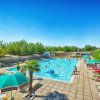 Grande piscina con ombrelloni e persone rilassate.