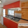 Cucina compatta con mobili rossi e piano cottura.