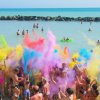 Spiaggia con persone che lanciano polveri colorate nell'aria.