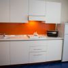 Cucina moderna con mobili bianchi e parete arancione.