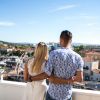 Coppia abbracciata su un balcone con vista sulla città.