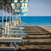 Spiaggia con sedie a sdraio e ombrelloni blu.