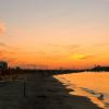Spiaggia al tramonto con ombrelloni chiusi.