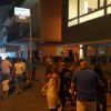 Persone camminano di notte davanti a un hotel.