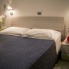 Letto matrimoniale con copriletto blu e piantina sulla sinistra.