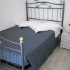 Letto matrimoniale con testiera in metallo, copriletto blu e pianta a sinistra.