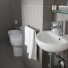 Bagno moderno con lavabo bianco e asciugamani appesi.