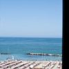 Vista mare da una finestra, con spiaggia affollata.