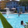 Persone in una piscina con fontana, edifici dietro.