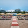 Spiaggia con ombrelloni gialli e lettini, hotel sullo sfondo.