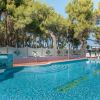 Piscina con mosaici blu e verde, immersa nel verde degli alberi.