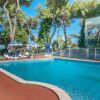 Piscina con sedie a sdraio e ombrelloni sotto gli alberi.