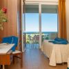 Camera d'hotel con balcone vista mare e fiori sul tavolo.