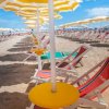 Spiaggia con sdraio rosse e ombrelloni gialli.