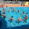 Persone in piscina che si tengono per mano in cerchio.