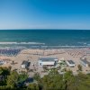 Spiaggia affollata con ombrelloni colorati e mare blu.