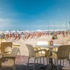 Tavoli esterni e spiaggia con ombrelloni.