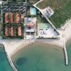 Vista aerea di un complesso con piscina, villette e spiaggia.