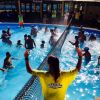 Persone che giocano in piscina con una rete da pallavolo.