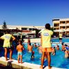 Animatori e bambini giocano in piscina all'aperto.