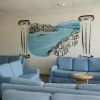 Divani blu davanti a un murale con paesaggio costiero.